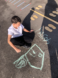 pupil drawing on the playground with chalk