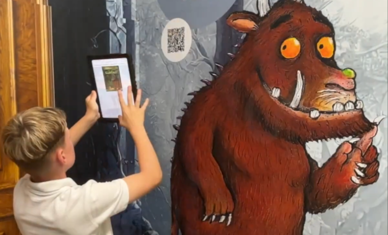 a young boy uses an ipad to scan a book QR code